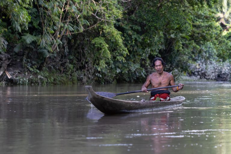 Mentawai shaman in canoe on Siberut Island, Sumatra, Indonesia